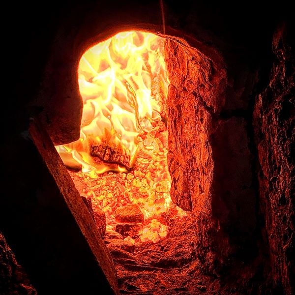 The warm glow of the stoke-hole in one of our wood-fired furnaces